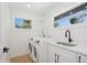 A bright and modern laundry room complete with washer, dryer, sink, and two windows at 2655 Bay St, Sarasota, FL 34237