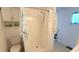 Simple, well-lit shower and toilet with white shower curtain and overhead storage at 3333 26Th E Ave # 1132, Bradenton, FL 34208