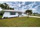Beautiful home with a white roof, lush landscaping, and a well-maintained lawn with a sprinkler system at 4102 Lakewood Ave, Bradenton, FL 34208