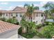 Exterior view of the building with well manicured grounds, mature palms, and red tile roof at 4254 Vicenza Dr # B, Venice, FL 34293