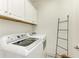 Bright laundry room featuring white cabinets, modern washer and dryer, and a convenient drying rack at 4416 Amalfi Ave, Sarasota, FL 34243
