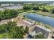 Aerial view of a home with a screened-in pool overlooking a pond, surrounded by lush greenery at 4627 56Th E Dr, Bradenton, FL 34203
