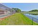 Spacious backyard featuring a screened-in pool area, lush lawn, and a tranquil pond view at 4627 56Th E Dr, Bradenton, FL 34203