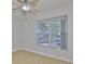 Bright bedroom with light walls, wood floors, a ceiling fan, and a large window overlooking the front yard at 4627 56Th E Dr, Bradenton, FL 34203