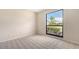 This is an empty bedroom with tile flooring and a large window overlooking the landscaping at 4812 Greywood Ln, Sarasota, FL 34235
