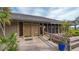 Exterior view of clubhouse, showing entrance doors, windows, and wooden deck with landscaping at 4812 Greywood Ln, Sarasota, FL 34235