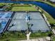 Aerial view of well-maintained tennis courts next to a lake in a lush community at 4927 Carova Way, Bradenton, FL 34211