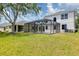 Expansive backyard featuring a screen-enclosed pool and lush green lawn with a view of the home's exterior at 5561 Burnt Branch Cir, Sarasota, FL 34232