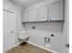 Bright laundry room with white cabinets and a wall-mounted sink, complete with wood-look floors and a clean design at 5561 Burnt Branch Cir, Sarasota, FL 34232
