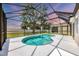 Kidney-shaped pool inside of a screened-in enclosure with a view of a green lawn and a lovely sunset at 5561 Burnt Branch Cir, Sarasota, FL 34232
