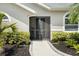 Close-up of a home's front door surrounded by lush bushes and a curved sidewalk at 5750 Carriage Dr, Sarasota, FL 34243