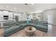 Open-concept living room with hardwood floors, grey couch and an adjoining modern kitchen and dining room at 5750 Carriage Dr, Sarasota, FL 34243
