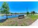 Enjoy the serene pond view from a community bench, enhanced by the calm water and sky at 6094 Amberly Dr, Bradenton, FL 34208
