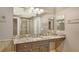 Spacious bathroom featuring a large granite vanity, sink, mirrors and a walk-in shower with glass doors at 610 Riviera Dunes Way # 308, Palmetto, FL 34221