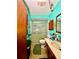Small bathroom with a sink, a toilet, a shower with a glass door, and decorated teal walls at 6265 Viola Ln, New Port Richey, FL 34653