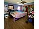 Cozy bedroom with wood flooring, a ceiling fan, and a bed with blue, purple, and pink walls at 6265 Viola Ln, New Port Richey, FL 34653