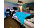 Bedroom with blue walls, a ceiling fan, a desk, a tv and a bed with blue and checkered linens at 6265 Viola Ln, New Port Richey, FL 34653