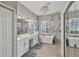 Gorgeous bathroom featuring dual sinks, a modern bathtub, marble walls, and elegant chandelier lighting at 6470 Indigo Bunting Pl, Lakewood Ranch, FL 34202