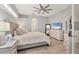 This main bedroom features a neutral color palette, ceiling fan, and a view into the en suite bathroom at 6470 Indigo Bunting Pl, Lakewood Ranch, FL 34202