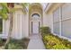 The entranceway features a white front door, tiled floor, and archway in a well landscaped walkway at 6504 Virginia Xing, University Park, FL 34201