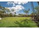 Large, green backyard with palm trees, blue skies, and boat lift, perfect for outdoor enjoyment at 705 89Th Nw Ct, Bradenton, FL 34209