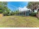 Spacious backyard with a screen-enclosed patio and mature trees at 7810 34Th E Ct, Sarasota, FL 34243