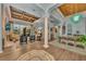 Open living room features high ceilings, wood beam accents, columns, and seamless access to the lanai at 8105 Warwick Gardens Ln, University Park, FL 34201