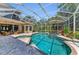 A screened-in pool with connected spa, patio furniture, and lush landscaping at 8105 Warwick Gardens Ln, University Park, FL 34201