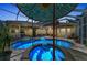 Screened-in pool with lighting, a decorative umbrella, and multiple seating areas at 8105 Warwick Gardens Ln, University Park, FL 34201