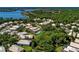 An aerial view shows houses nestled among lush trees near a lake, some with pools, in a tranquil neighborhood setting at 8408 Whispering Woods Ct, Lakewood Ranch, FL 34202