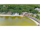 Scenic lake view featuring a sandy beach, a wooden pier, colorful kayaks, and a backdrop of lush trees at 8408 Whispering Woods Ct, Lakewood Ranch, FL 34202