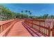 Scenic wooden boardwalk with a red railing leading to a gazebo, surrounded by lush greenery and a serene lake at 8408 Whispering Woods Ct, Lakewood Ranch, FL 34202