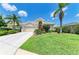Beautiful single-story home with a well-manicured lawn and lush landscaping, including palm trees at 8408 Whispering Woods Ct, Lakewood Ranch, FL 34202