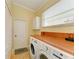 Well-lit laundry room features a front load washer and dryer, wood countertop, and plenty of storage space at 8408 Whispering Woods Ct, Lakewood Ranch, FL 34202