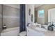 A modern bathroom featuring stylish grey tile, a shower-tub combo, sleek vanity and brushed nickel hardware at 8633 Snowfall St, Sarasota, FL 34241