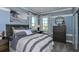 A comfortable bedroom with a queen sized bed, stylish dresser, ocean artwork, and views of the outdoors at 8633 Snowfall St, Sarasota, FL 34241