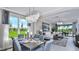 Elegant living area with large windows, modern chandelier, dining table and views of green space at 8633 Snowfall St, Sarasota, FL 34241