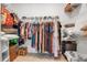A walk-in closet features rods full of clothing items, shelves above, and tile flooring at 10414 Spring Tide Way, Parrish, FL 34219