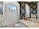 Modern bathroom featuring tropical wallpaper, a single sink, and a glass shower at 12240 Thornhill Ct, Lakewood Ranch, FL 34202