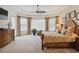 Bright main bedroom with a decorative ceiling fan, large windows, and a wooden bed frame at 12240 Thornhill Ct, Lakewood Ranch, FL 34202