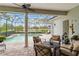 Screened-in patio with brick flooring, comfortable seating area, and a view of the sparkling pool and landscaped backyard at 12240 Thornhill Ct, Lakewood Ranch, FL 34202