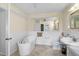 Bathroom features a soaking tub, large mirror, pedestal sink and neutral tile at 1227 Waterside Ln, Venice, FL 34285