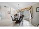 Elegant dining room featuring a chandelier, neutral walls, and a bay window adorned with decorative curtains at 1227 Waterside Ln, Venice, FL 34285