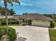 A bright home with a white garage door with palm trees in the yard at 1227 Waterside Ln, Venice, FL 34285