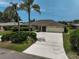 Charming single-story home features a concrete driveway leading to an attached two-car garage and tropical landscaping at 1227 Waterside Ln, Venice, FL 34285