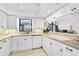 Well-lit kitchen featuring white cabinets, tile backsplash, and a view to the dining area at 1227 Waterside Ln, Venice, FL 34285