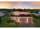 Elegant two-story home featuring a tile roof, arched entryway, and lush landscaping at 13706 American Prairie Pl, Lakewood Ranch, FL 34211