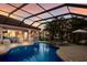 Large screened-in pool with a spa and outdoor kitchen area against a vibrant sunset backdrop at 13706 American Prairie Pl, Lakewood Ranch, FL 34211