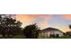 Spacious backyard featuring a lush lawn and screened-in lanai, set against a vibrant sunset sky at 13848 American Prairie Pl, Lakewood Ranch, FL 34211