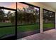 Screened-in patio with a view of lush green landscaping and a beautiful sunset sky at 13848 American Prairie Pl, Lakewood Ranch, FL 34211